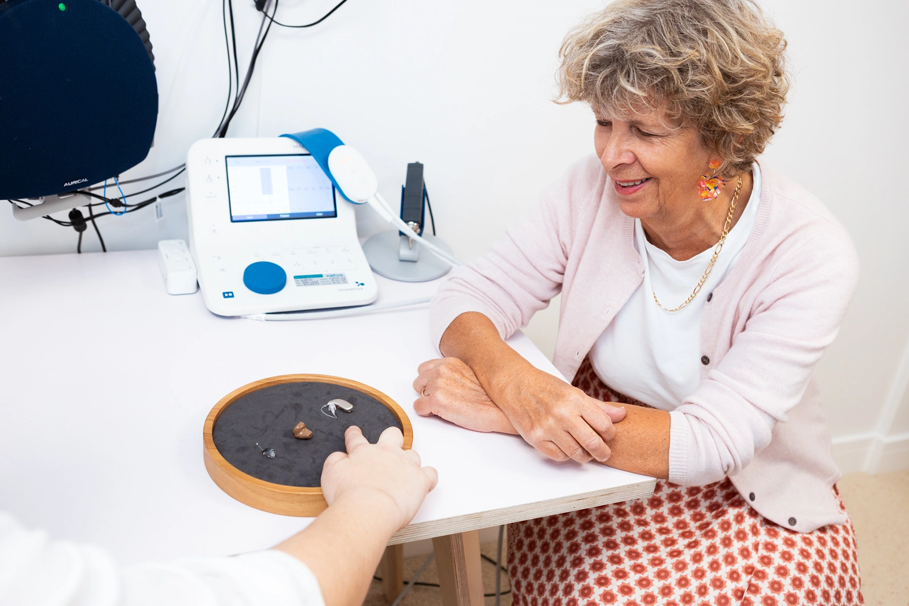 A woman sat during her audiology appointment looking at hearing aids