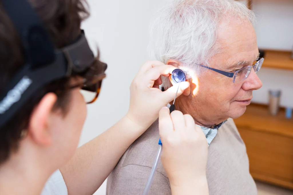 A man having microsuction ear wax removal performed by a female audiologist.