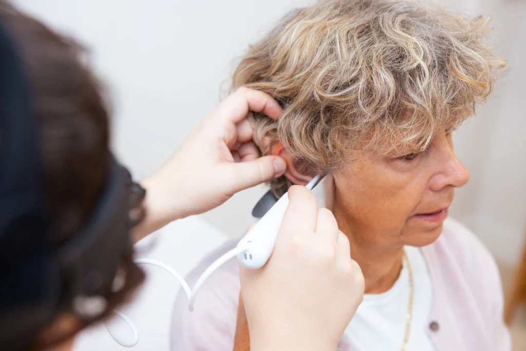 Female patient having irrigation ear wax removal performed by female audiologist.