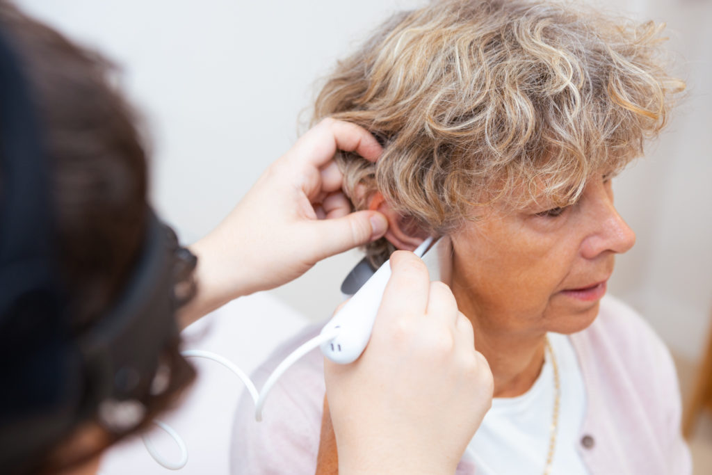 An audiologist is using irrigation to remove wax from a woman's right ear.