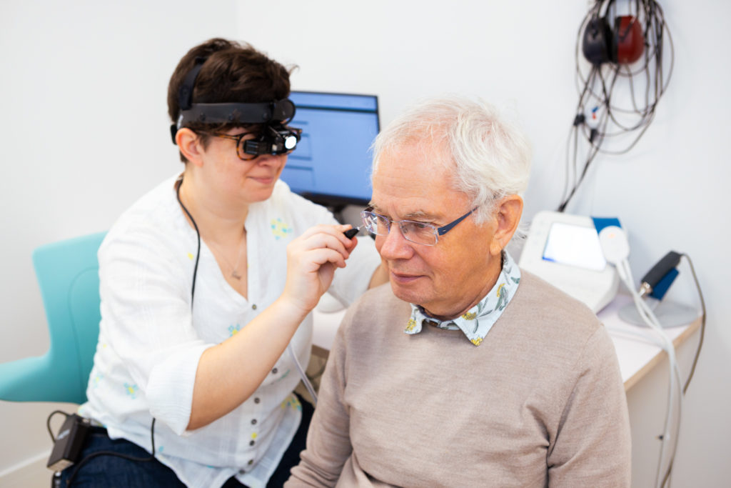 An audiologist is removing wax from a patients right ear using microsuction.